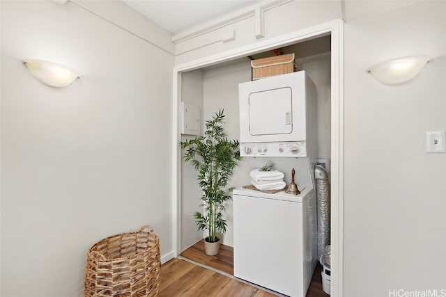 laundry area with hardwood / wood-style flooring and stacked washer and clothes dryer