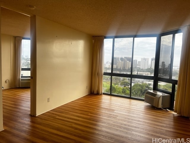 empty room featuring hardwood / wood-style flooring, a healthy amount of sunlight, and a wall of windows