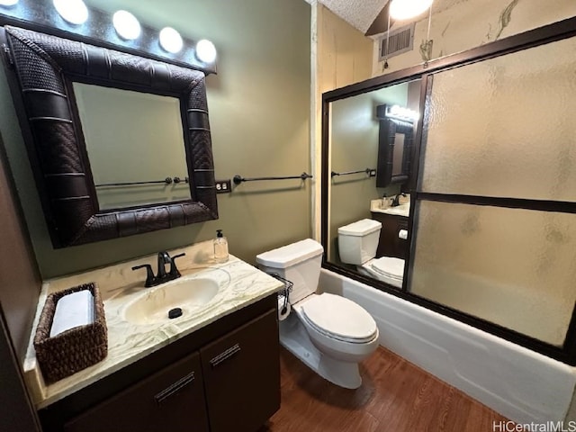 full bathroom featuring toilet, wood-type flooring, shower / bath combination with glass door, a textured ceiling, and vanity