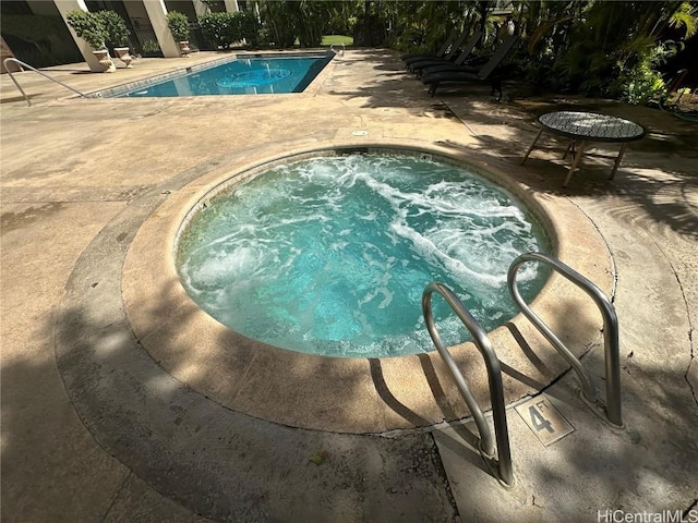 pool with a patio area and a community hot tub