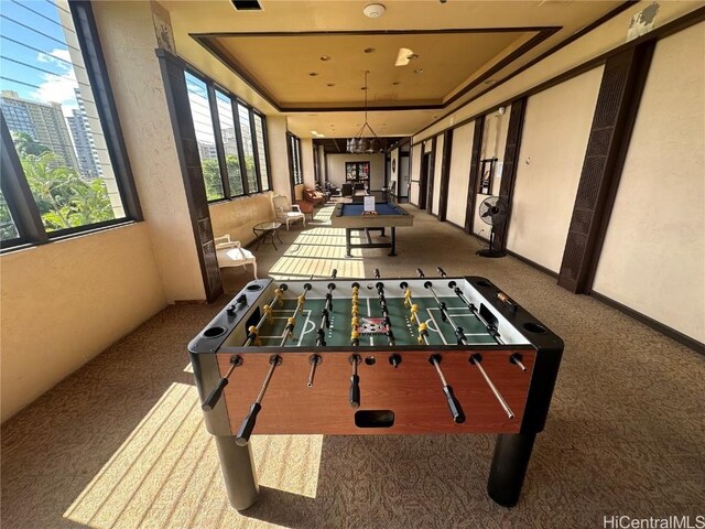 game room with a raised ceiling and carpet