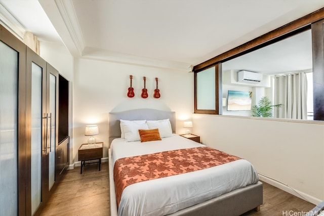 bedroom featuring a wall mounted air conditioner, crown molding, and hardwood / wood-style flooring