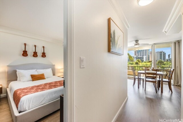 bedroom with hardwood / wood-style floors, expansive windows, and crown molding