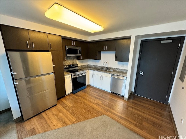 kitchen with dark brown cabinets, wood-type flooring, sink, appliances with stainless steel finishes, and tasteful backsplash