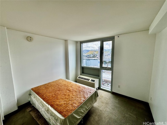 bedroom with a wall mounted AC and dark colored carpet