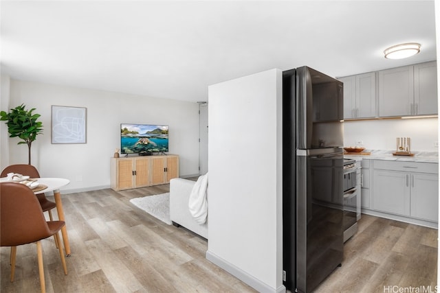 kitchen featuring gray cabinets, double oven range, and light hardwood / wood-style flooring