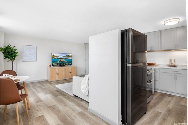 kitchen with light countertops, gray cabinetry, light wood-style flooring, and freestanding refrigerator