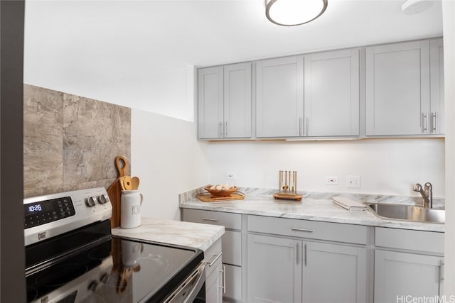 kitchen featuring electric stove, gray cabinets, sink, and light stone counters