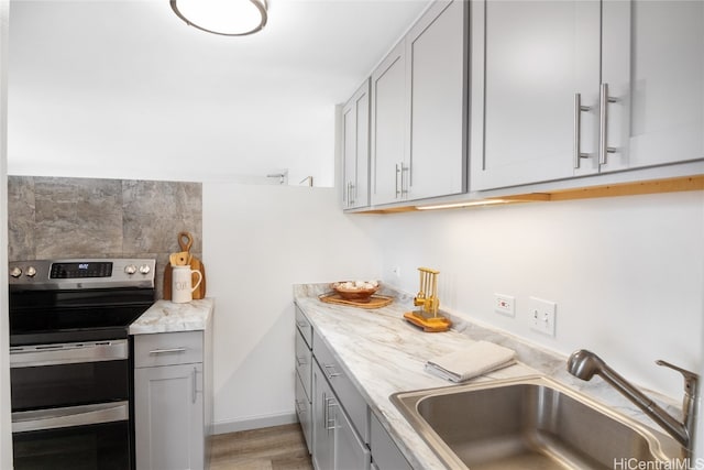 kitchen featuring sink, gray cabinetry, decorative backsplash, electric range, and light stone countertops