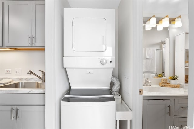 clothes washing area featuring stacked washer / dryer and sink