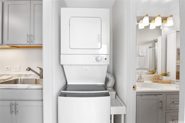 laundry room featuring a sink, stacked washer and clothes dryer, and laundry area