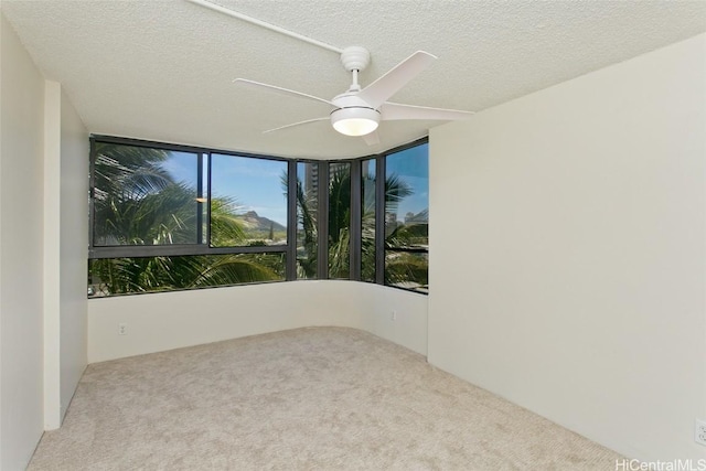 carpeted empty room with ceiling fan and a textured ceiling