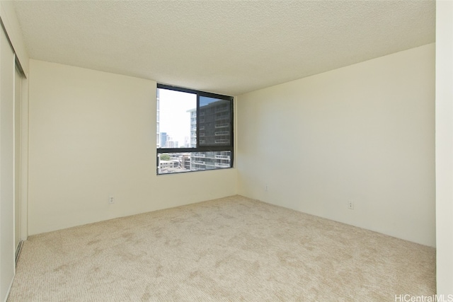 unfurnished room featuring light carpet and a textured ceiling