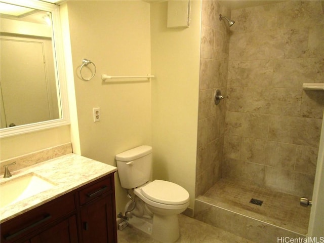 bathroom featuring vanity, a tile shower, and toilet