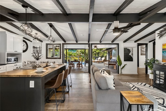 kitchen with wood-type flooring, a kitchen island, decorative light fixtures, white cabinets, and a breakfast bar