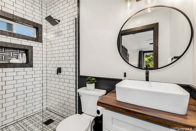 bathroom with toilet, vanity, and a tile shower