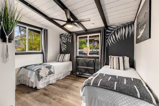 bedroom with multiple windows, hardwood / wood-style flooring, lofted ceiling with beams, and ceiling fan