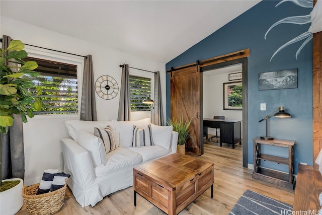 living room featuring lofted ceiling, a barn door, and light wood-type flooring