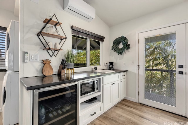 bar featuring wine cooler, plenty of natural light, white cabinets, and stacked washing maching and dryer