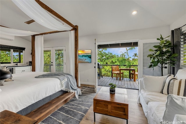 bedroom featuring an AC wall unit, lofted ceiling, light hardwood / wood-style flooring, and access to exterior