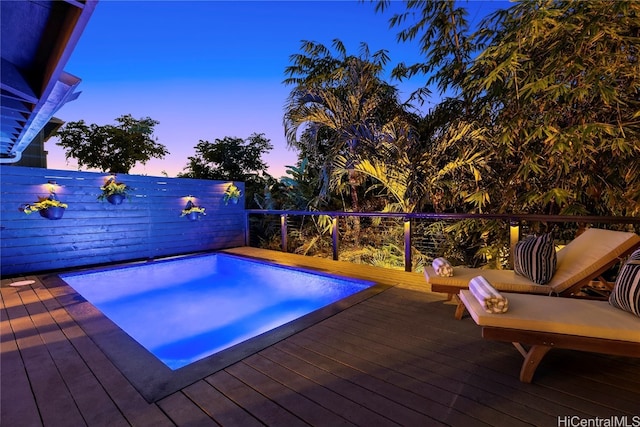 pool at dusk featuring a wooden deck