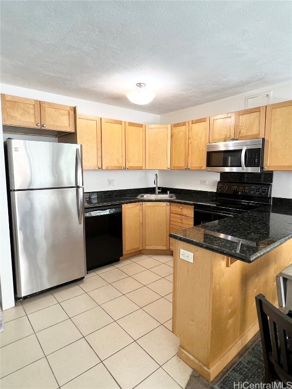 kitchen with kitchen peninsula, dark stone counters, light tile patterned flooring, black appliances, and sink