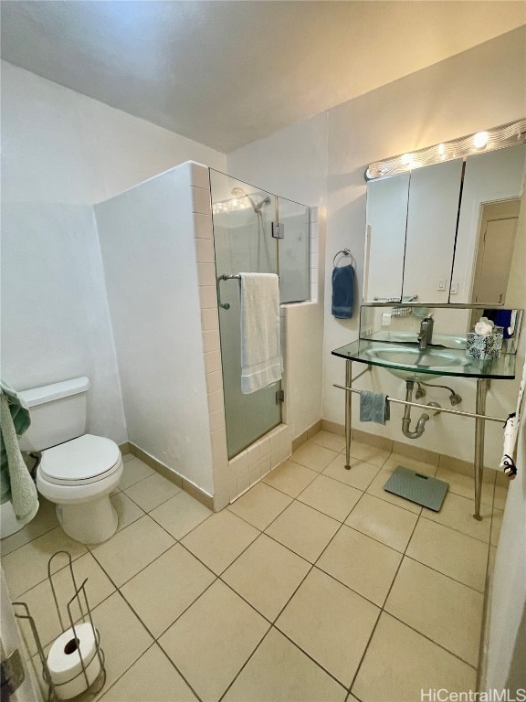 bathroom with toilet, walk in shower, sink, and tile patterned floors