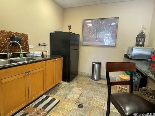 kitchen with sink, a drop ceiling, and black refrigerator