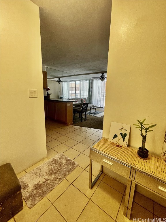 hall featuring a textured ceiling and light tile patterned floors