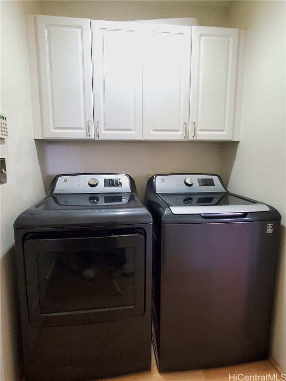 clothes washing area featuring cabinets and washing machine and clothes dryer