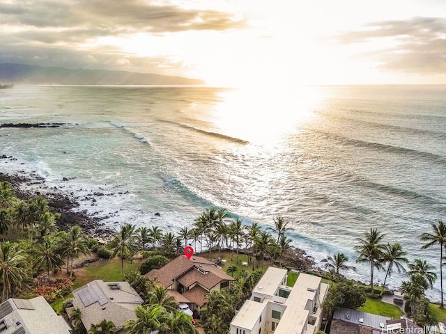 aerial view at dusk featuring a water view and a view of the beach