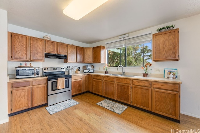 kitchen with appliances with stainless steel finishes, sink, and light wood-type flooring