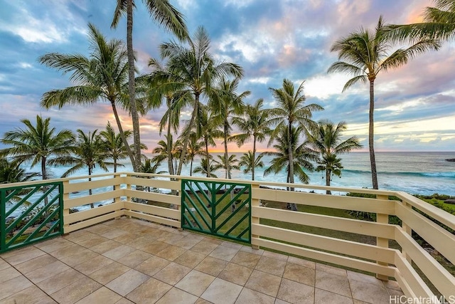 patio terrace at dusk featuring a water view and a balcony