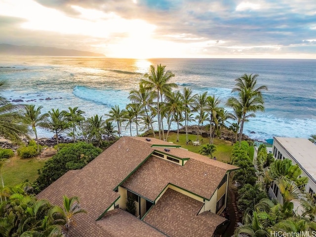 aerial view at dusk with a water view and a beach view