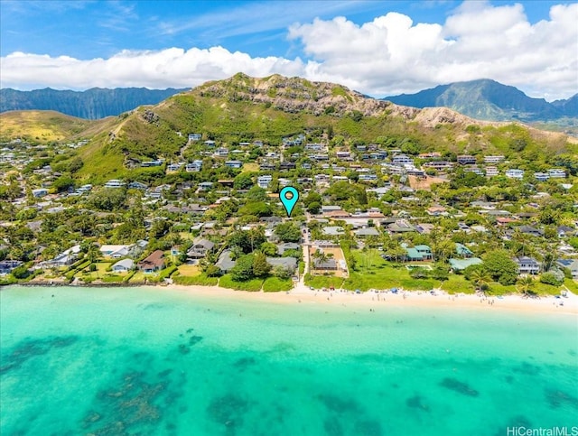 drone / aerial view with a water and mountain view, a beach view, and a residential view