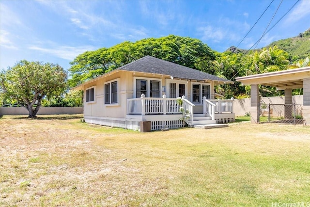view of front of property with roof with shingles, fence, and a front yard