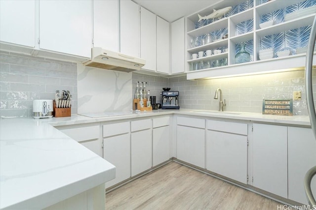 kitchen with a sink, white electric cooktop, backsplash, and under cabinet range hood