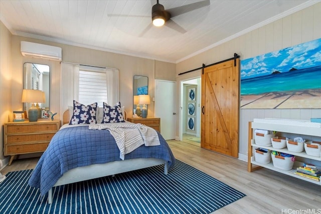 bedroom with crown molding, wood finished floors, a barn door, a wall mounted AC, and a ceiling fan