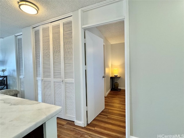 hall with baseboards, dark wood-type flooring, and a textured ceiling