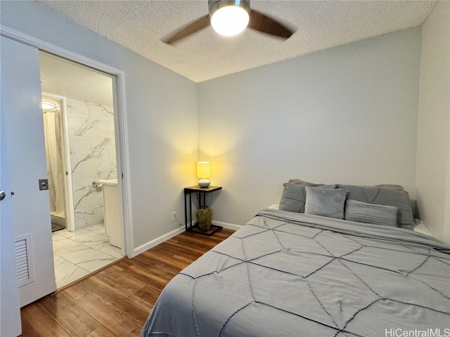 bedroom featuring a ceiling fan, a textured ceiling, ensuite bath, wood finished floors, and baseboards