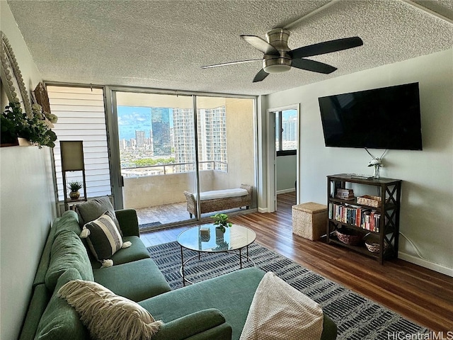 living room with ceiling fan, baseboards, expansive windows, wood finished floors, and a textured ceiling