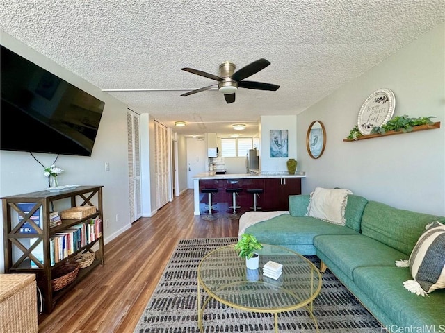 living area with a ceiling fan, dark wood-style floors, and a textured ceiling