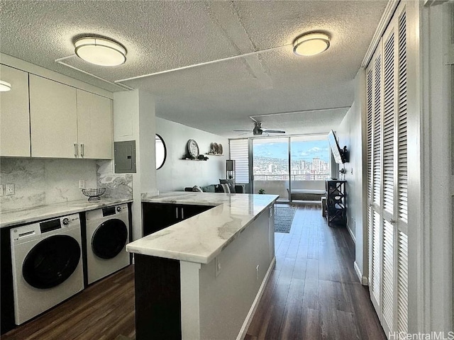 kitchen with a peninsula, electric panel, dark wood-style flooring, white cabinetry, and washing machine and dryer