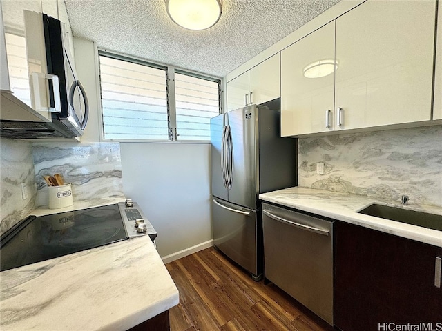 kitchen featuring light countertops, stainless steel appliances, a textured ceiling, white cabinetry, and dark wood-style flooring