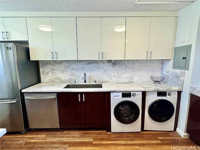 laundry room featuring separate washer and dryer, sink, electric panel, and light hardwood / wood-style floors