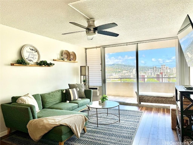 living room with ceiling fan, cooling unit, floor to ceiling windows, wood-type flooring, and a textured ceiling