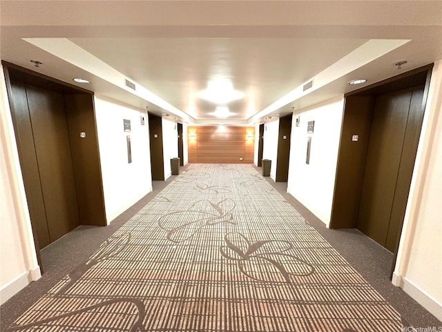 hallway with elevator, visible vents, and carpet floors