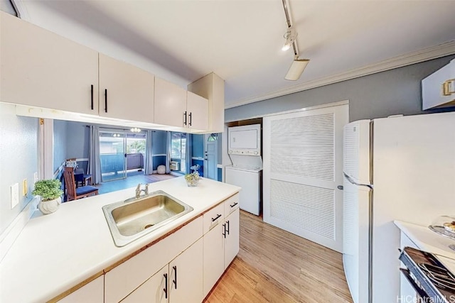 kitchen with sink, crown molding, stacked washer and clothes dryer, white refrigerator, and track lighting