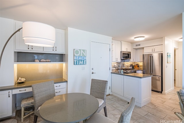 kitchen featuring appliances with stainless steel finishes, sink, light wood-type flooring, white cabinetry, and decorative backsplash