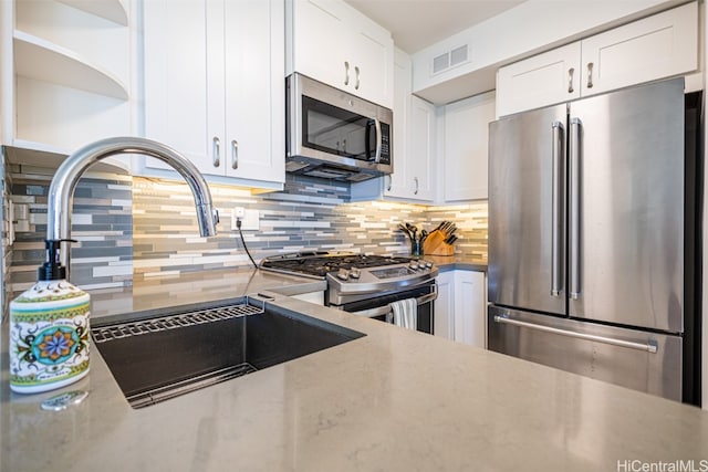 kitchen featuring sink, white cabinets, stainless steel appliances, and tasteful backsplash